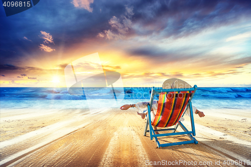 Image of Woman in chaise-lounge relaxing at sunset 