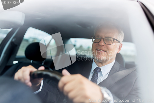 Image of happy senior businessman driving car