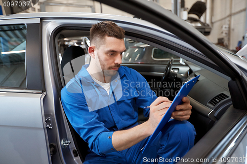 Image of auto mechanic man with clipboard at car workshop