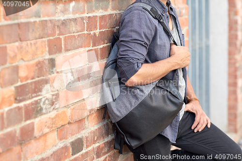 Image of close up of man with backpack standing at wall