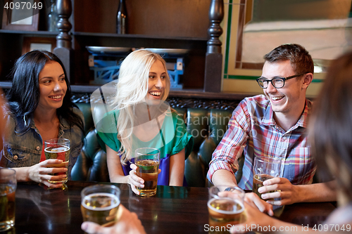 Image of happy friends drinking beer at bar or pub