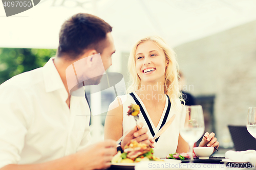 Image of happy couple eating dinner at restaurant terrace