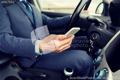 Image of close up of man with smartphone driving car