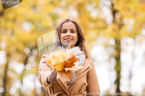 Image of beautiful woman with maple leaves in autumn park