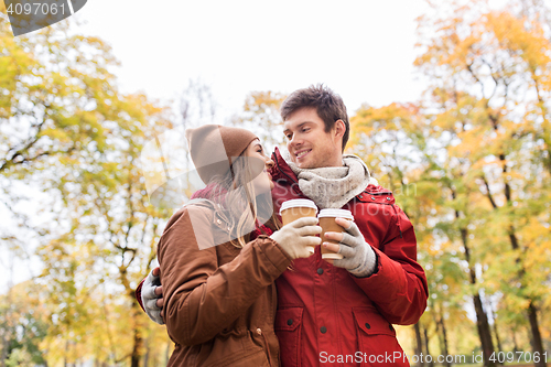 Image of happy couple with coffee walking in autumn park