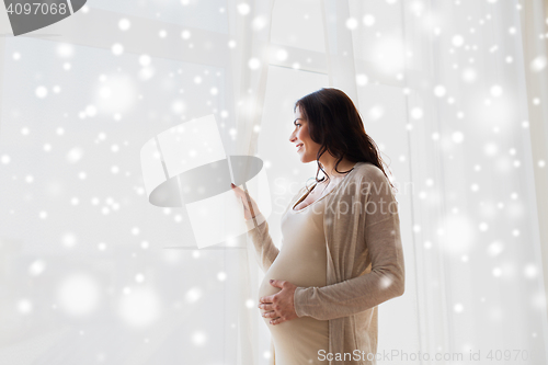 Image of happy pregnant woman looking to window