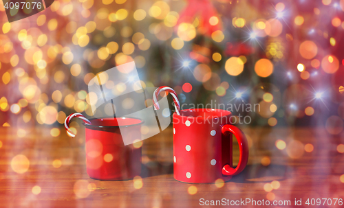 Image of christmas candy canes in cups on wooden table
