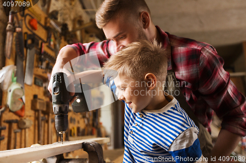 Image of father and son with drill working at workshop