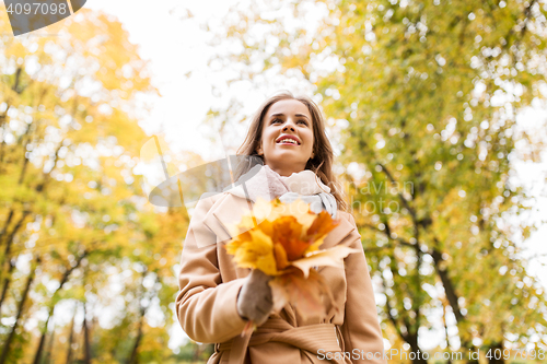 Image of beautiful woman with maple leaves in autumn park