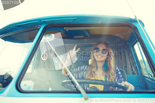 Image of smiling young hippie woman driving minivan car