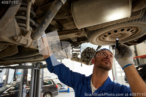 Image of mechanic man with flashlight repairing car at shop