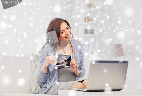 Image of happy pregnant woman with ultrasound image at home