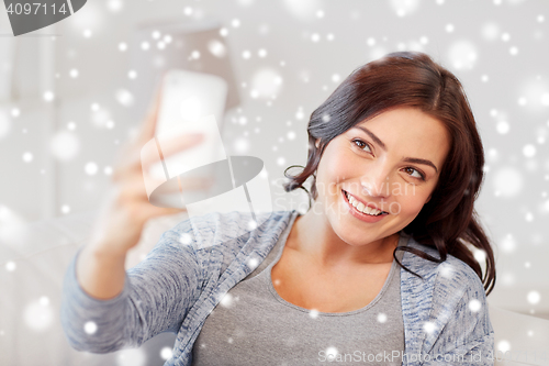 Image of happy woman taking selfie with smartphone at home