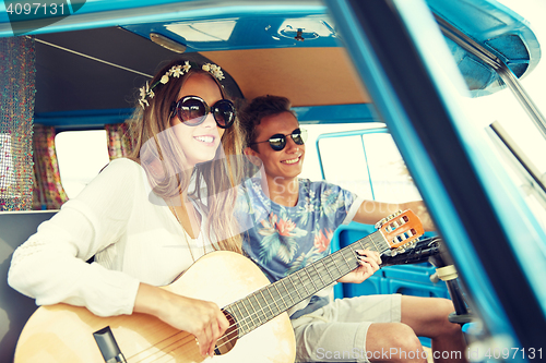 Image of smiling hippie couple with guitar in minivan car