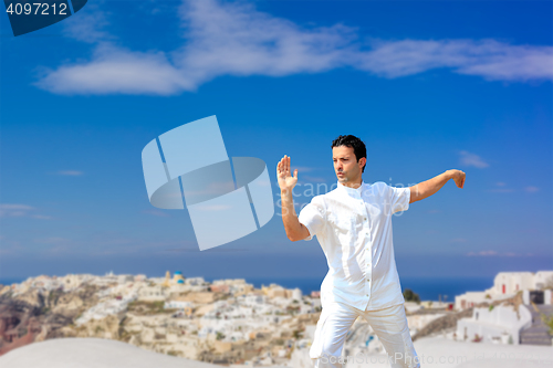 Image of Handsome man practicing Tai Chi of the rooftops in Oia Santorini