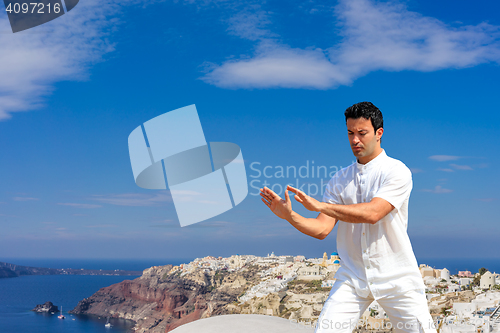 Image of Handsome man practicing Tai Chi of the rooftops in Oia Santorini