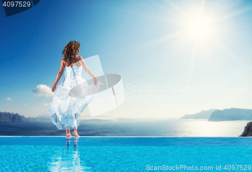 Image of Bride standing on the edge on the infinity pool in Santorini 