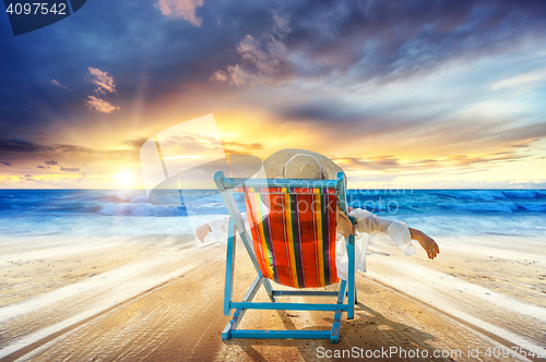 Image of Woman in chaise-lounge relaxing at sunset 