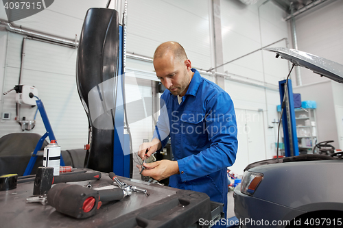 Image of mechanic man with wrench repairing car at workshop