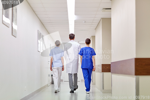 Image of group of medics or doctors walking along hospital