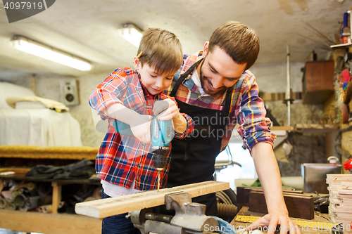 Image of father and son with drill working at workshop