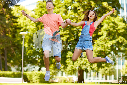 Image of happy teenage couple jumping at summer park