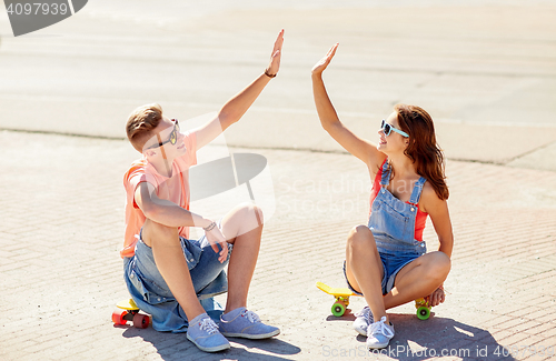 Image of teenage couple with skateboards on city street