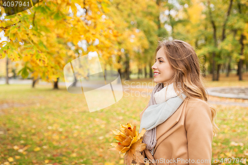 Image of beautiful woman with maple leaves in autumn park