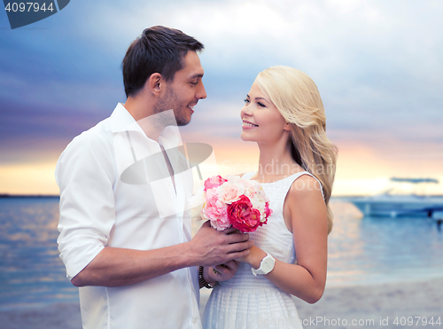 Image of happy couple with flowers over beach background