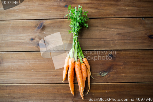 Image of close up of carrot bunch on wooden table