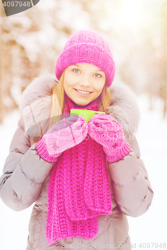 Image of smiling young woman with cup in winter forest