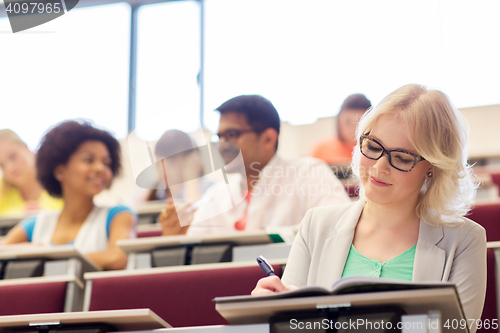 Image of student girl writing to notebook in lecture hall