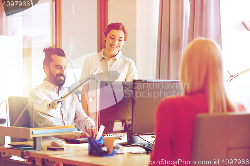 Image of happy creative team with computers in office