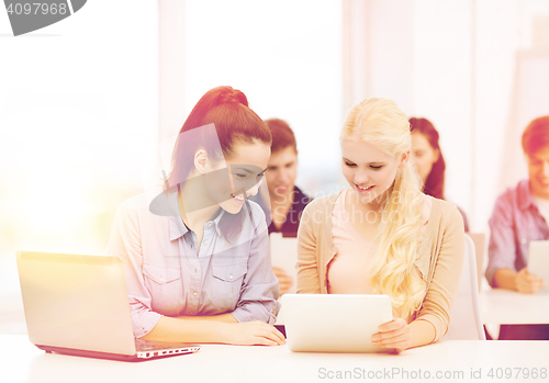 Image of two smiling students with laptop and tablet pc