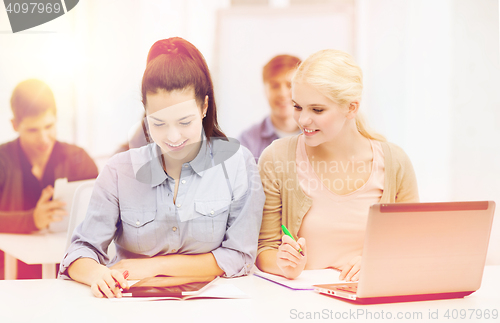 Image of two smiling students with laptop and tablet pc