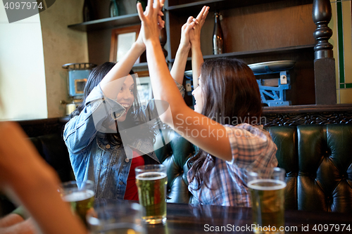 Image of happy friends with beer celebrating at bar or pub