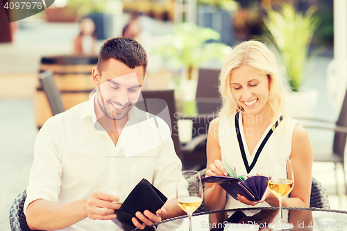 Image of happy couple with wallet paying bill at restaurant