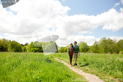 Image of happy couple with backpacks hiking outdoors