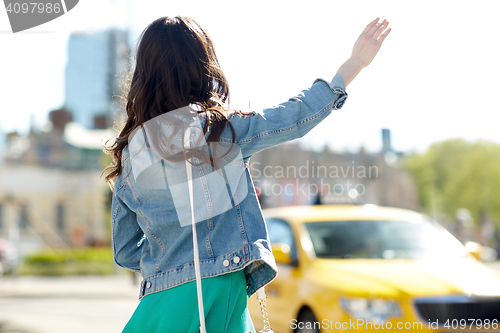 Image of young woman or girl catching taxi on city street