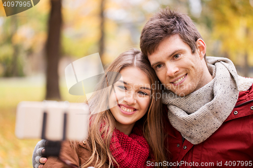 Image of couple taking selfie by smartphone in autumn park