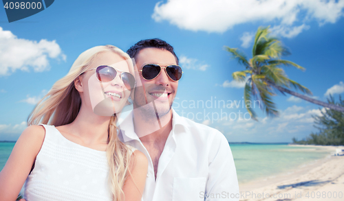 Image of couple in shades over tropical beach background