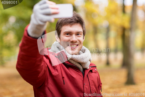 Image of man taking selfie by smartphone in autumn park