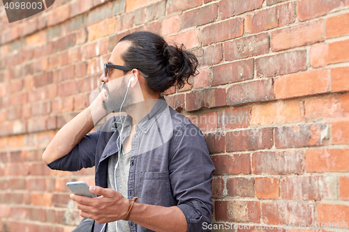 Image of man with earphones and smartphone on street