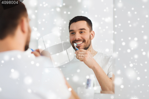 Image of man with toothbrush cleaning teeth at bathroom