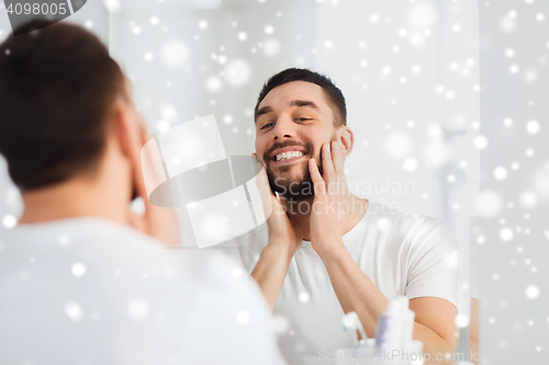 Image of happy young man looking to mirror at home bathroom