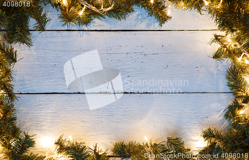 Image of Christmas wood background with luminous garland and pine branches
