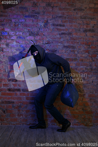 Image of Crook near wall with bag