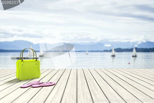 Image of green bag on a wooden jetty with sailing boats in the background