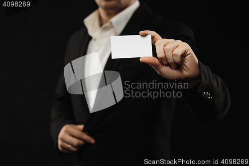 Image of The businessman in black costume showing credit card or visiting card