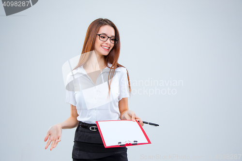 Image of The smiling young business woman with pen and tablet for notes on gray background